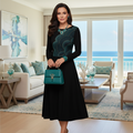 Confident woman in black dress with teal geometric design accessorized with teal necklace, bracelet and handbag in luxurious coastal living room